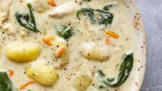 A bowl of slow cooker chicken gnocchi soup topped with cracked black pepper.