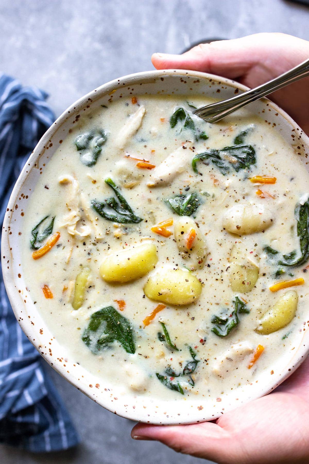 A bowl of slow cooker chicken gnocchi soup topped with cracked black pepper.