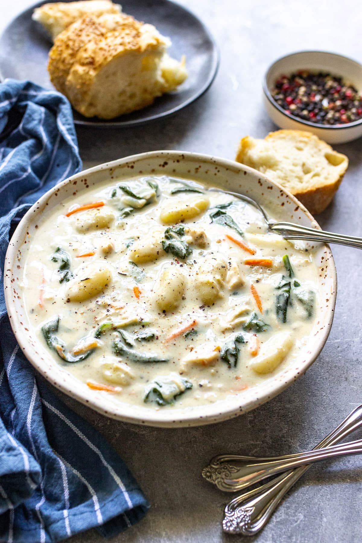 A bowl of slow cooker chicken gnocchi soup topped with cracked black pepper.