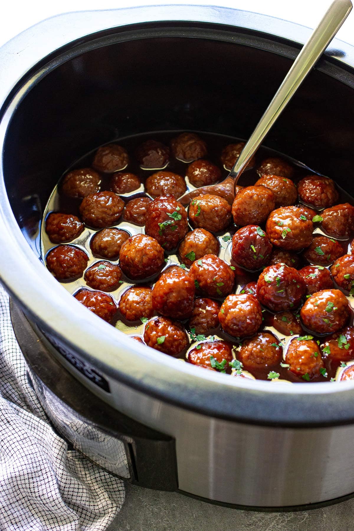 Cooked slow cooker grape jelly meatballs swimming in a lot of sauce in a slow cooker.