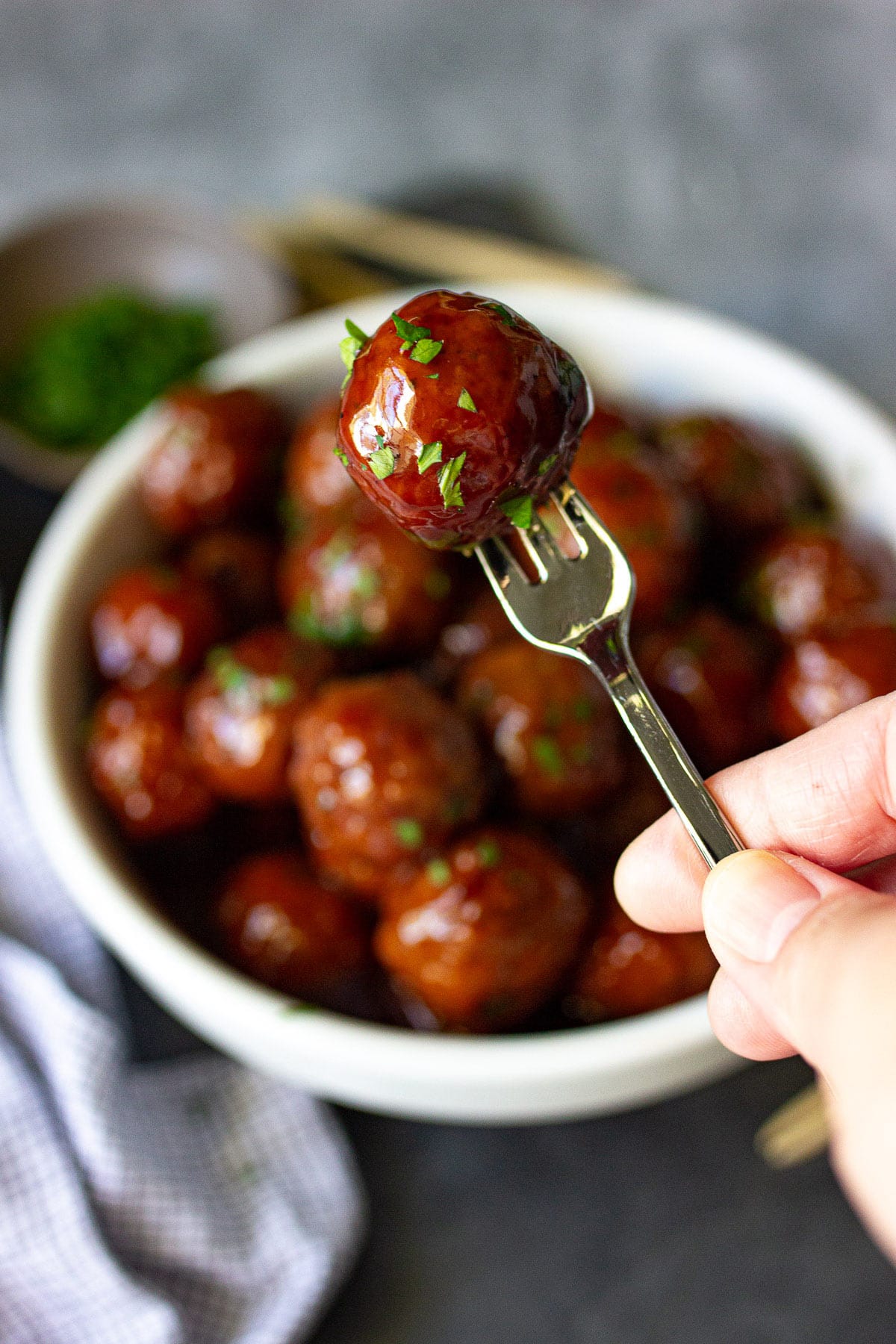 A slow cooker grape jelly meatball on an mini appetizer fork.