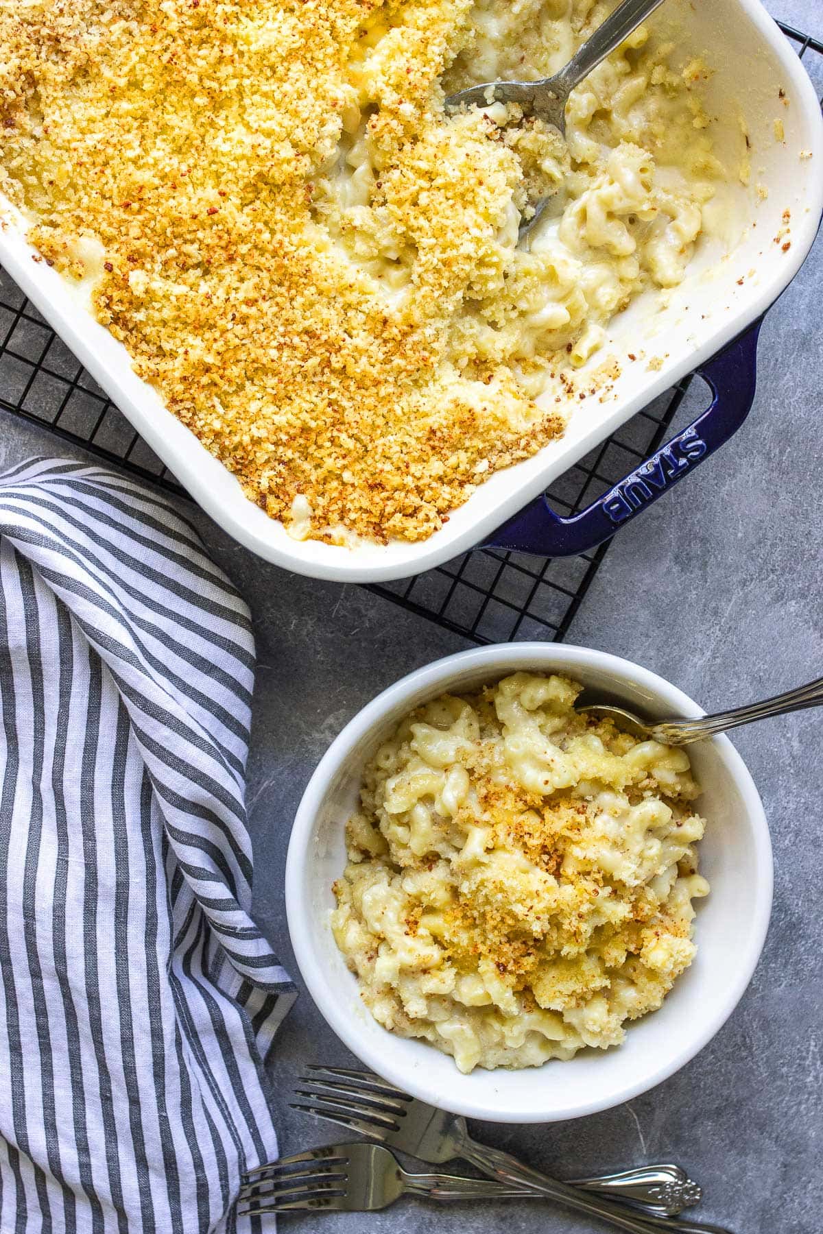 Baked mac and cheese in a white bowl and 9x13 blue casserole dish.