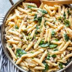 Creamy sausage pasta in a stainless steel skillet.