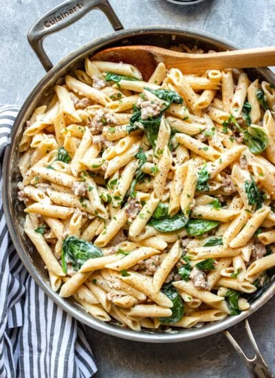 Creamy sausage pasta in a stainless steel skillet.