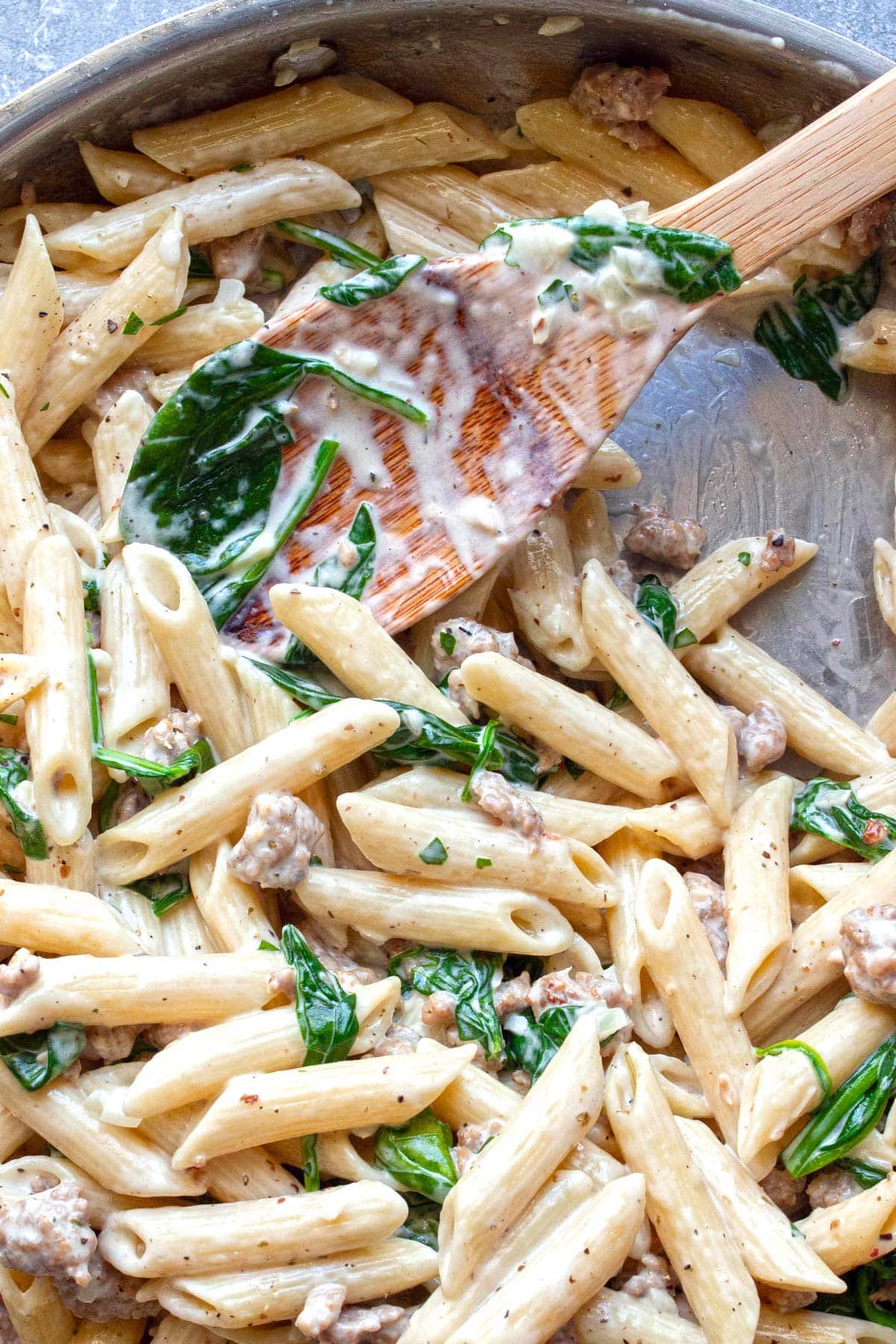 Close up of creamy sausage pasta in a skillet.