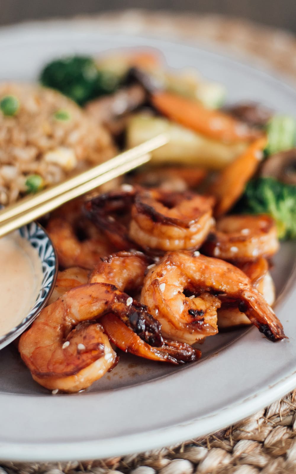 A plate full of hibachi shrimp, hibachi rice and hibachi vegetables with a side of yum yum sauce.