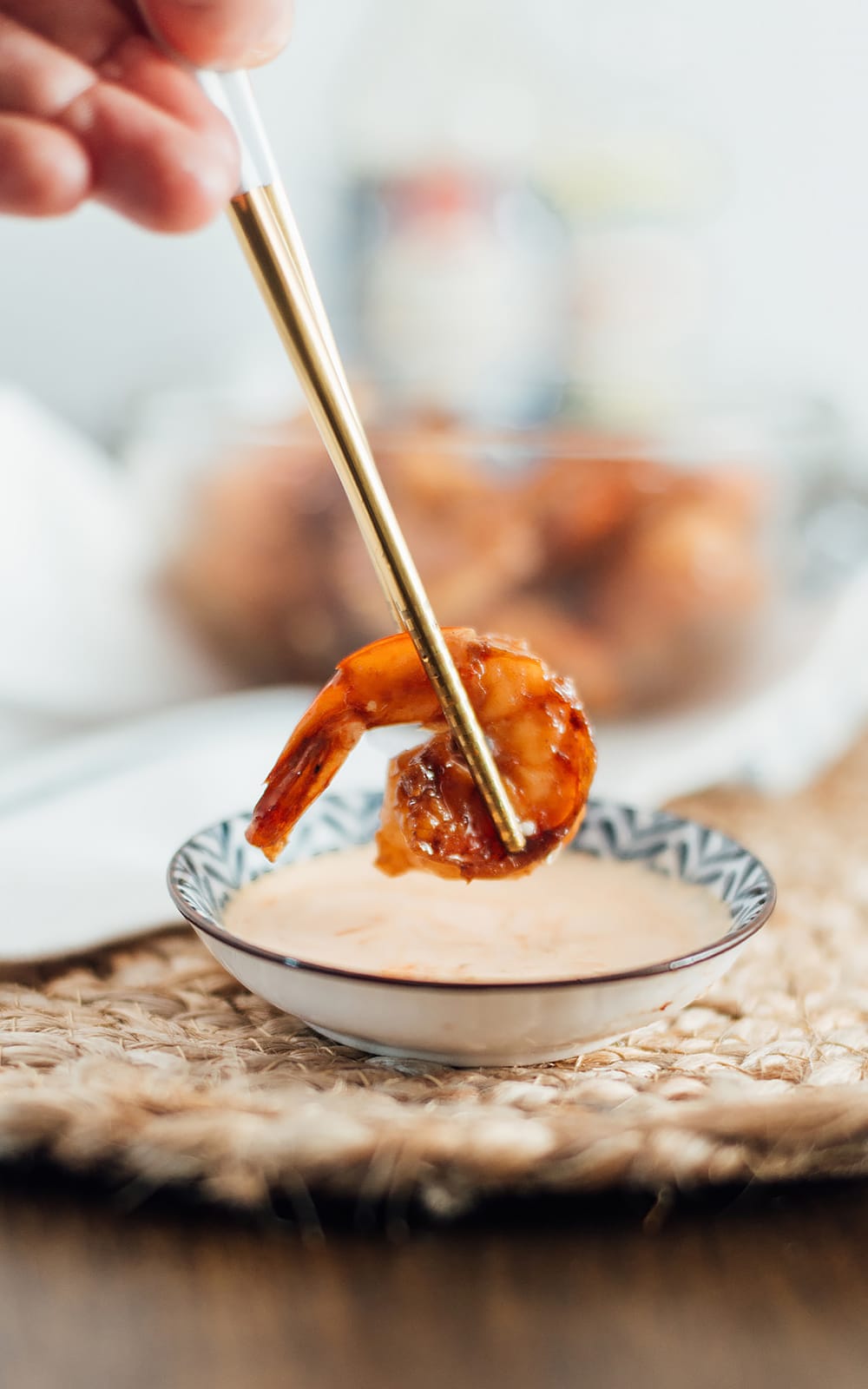 Hibachi shrimp being dipped into a bowl of yum yum sauce.