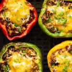 Close up shot of red, green and yellow air fryer stuffed peppers in an air fryer.