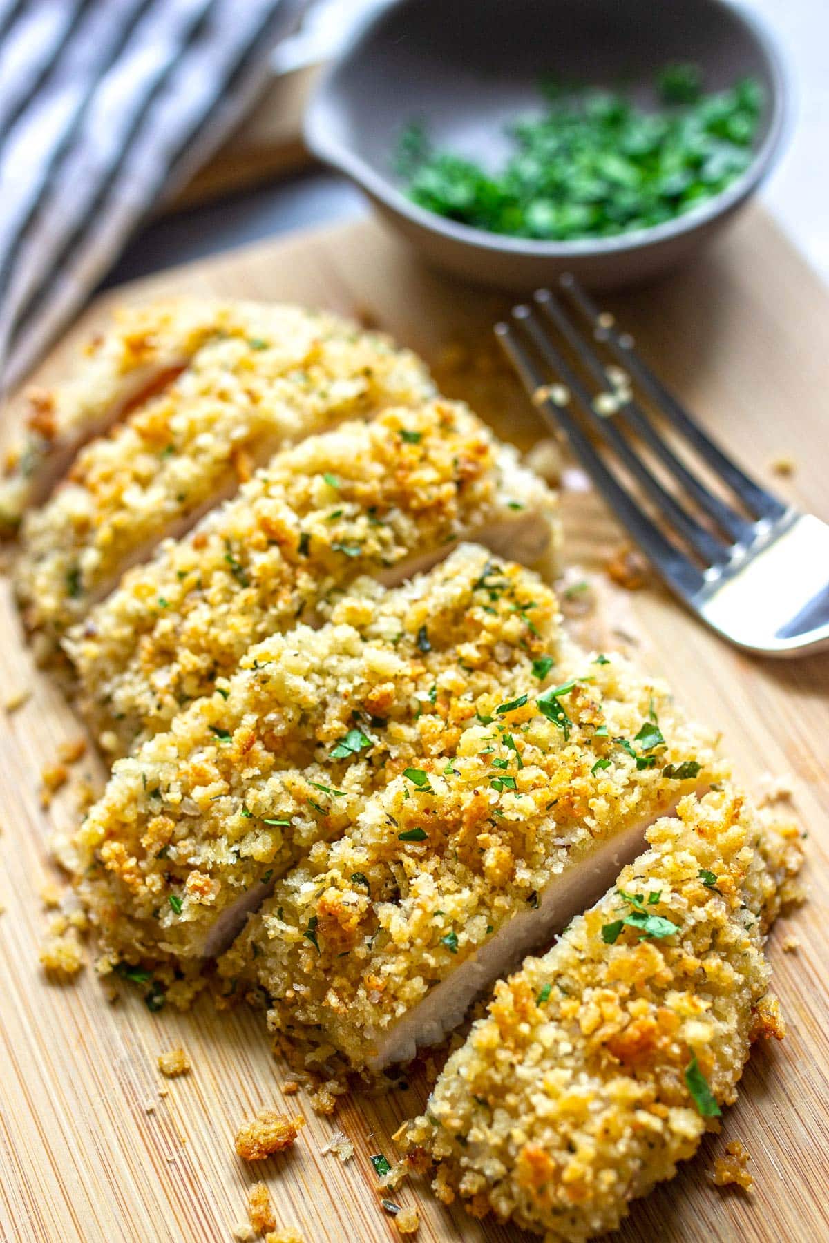 Sliced Parmesan crusted chicken on a cutting board.