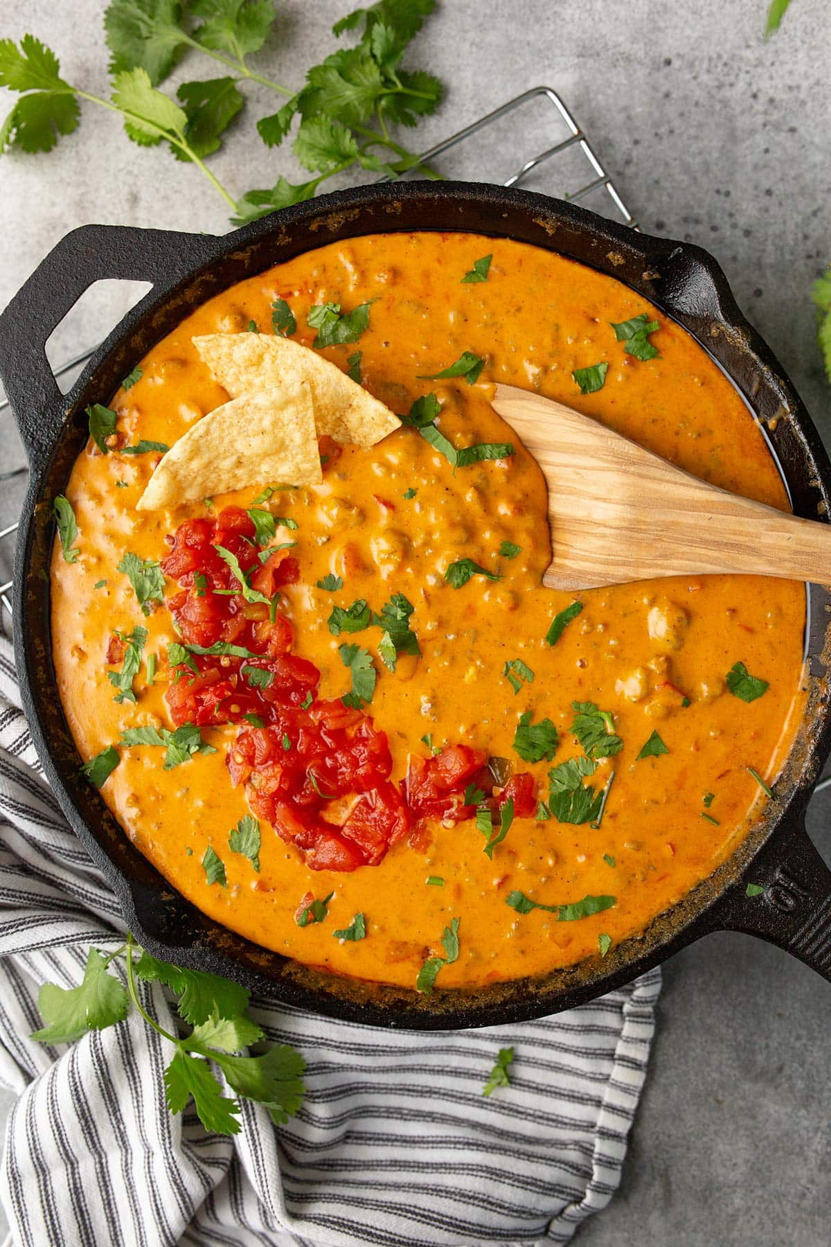 Velveeta Rotel sausage dip in a cast iron skillet topped with diced tomatoes and fresh cilantro.