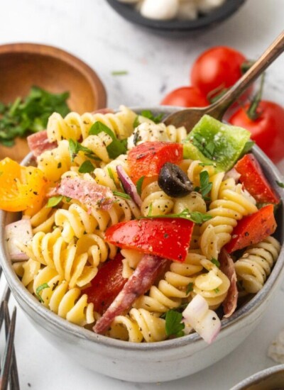 A serving bowl full to the brim with Italian pasta salad topped with cracked pepper.