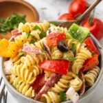 A serving bowl full to the brim with Italian pasta salad topped with cracked pepper.