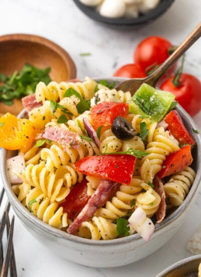 A serving bowl full to the brim with Italian pasta salad topped with cracked pepper.