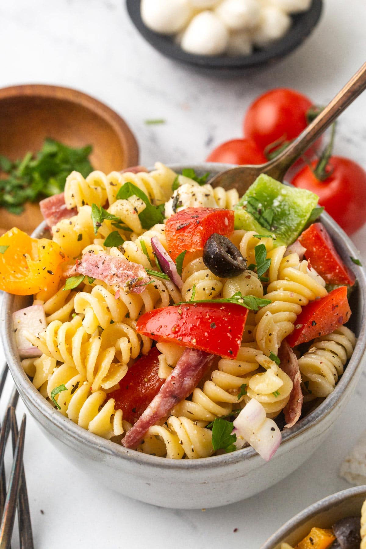 A serving bowl full to the brim with Italian pasta salad topped with cracked pepper.