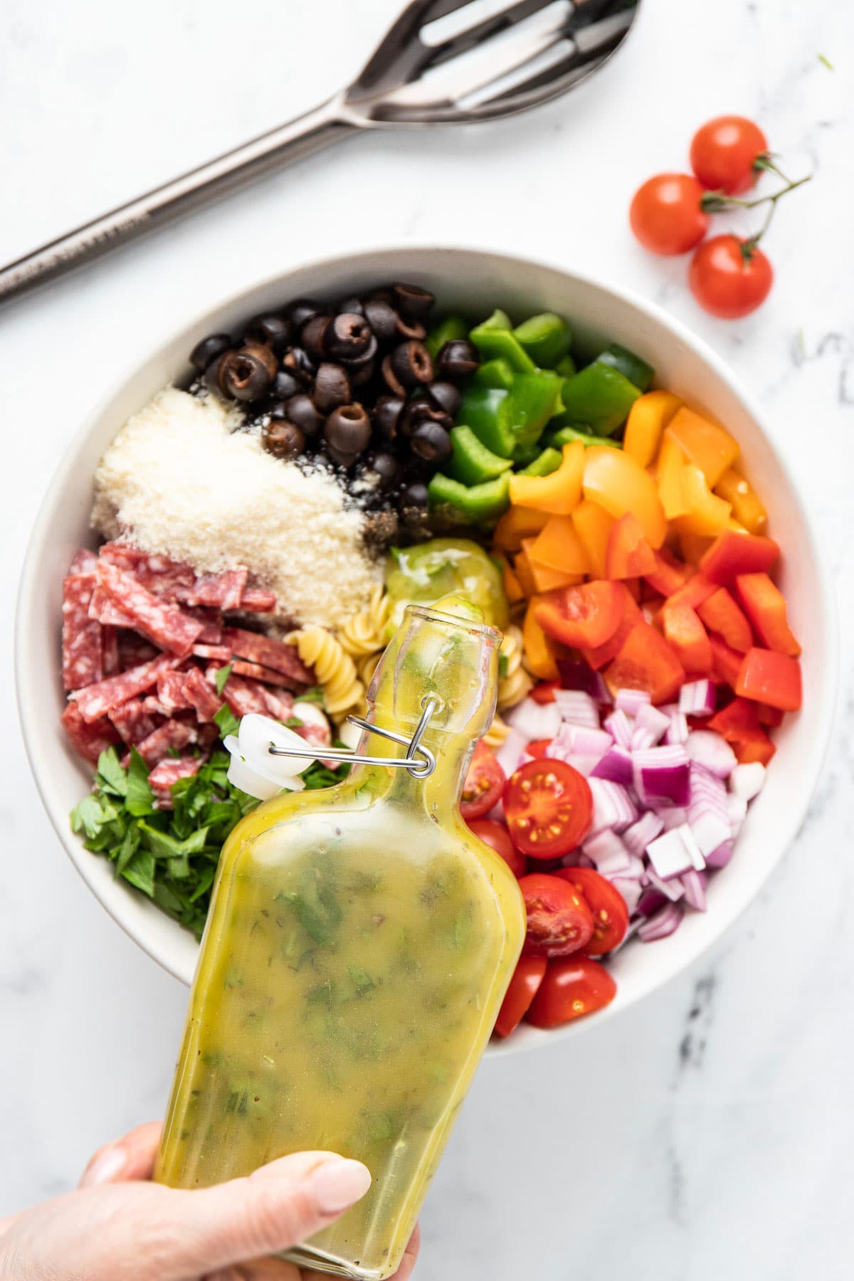 Italian pasta salad in a mixing bowl with dressing poured into it.