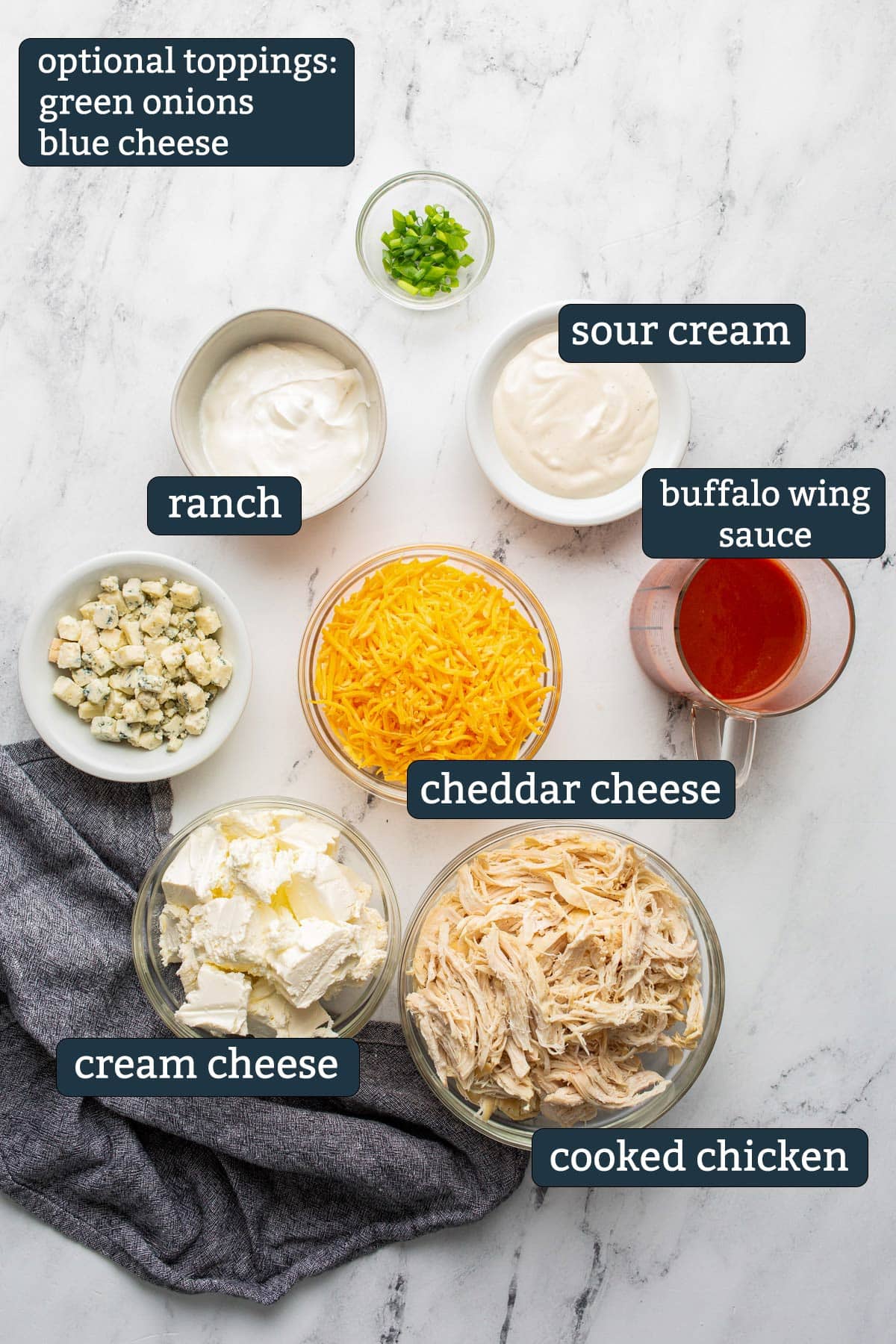 Ingredients to make slow cooker buffalo chicken dip in prep bowls.