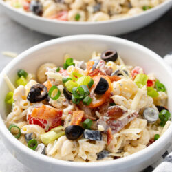 Bacon ranch pasta salad in a white bowl topped with chopped green onions.