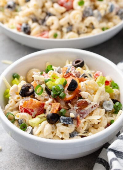 Bacon ranch pasta salad in a white bowl topped with chopped green onions.