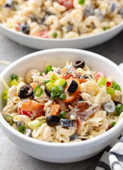 Bacon ranch pasta salad in a white bowl topped with chopped green onions.