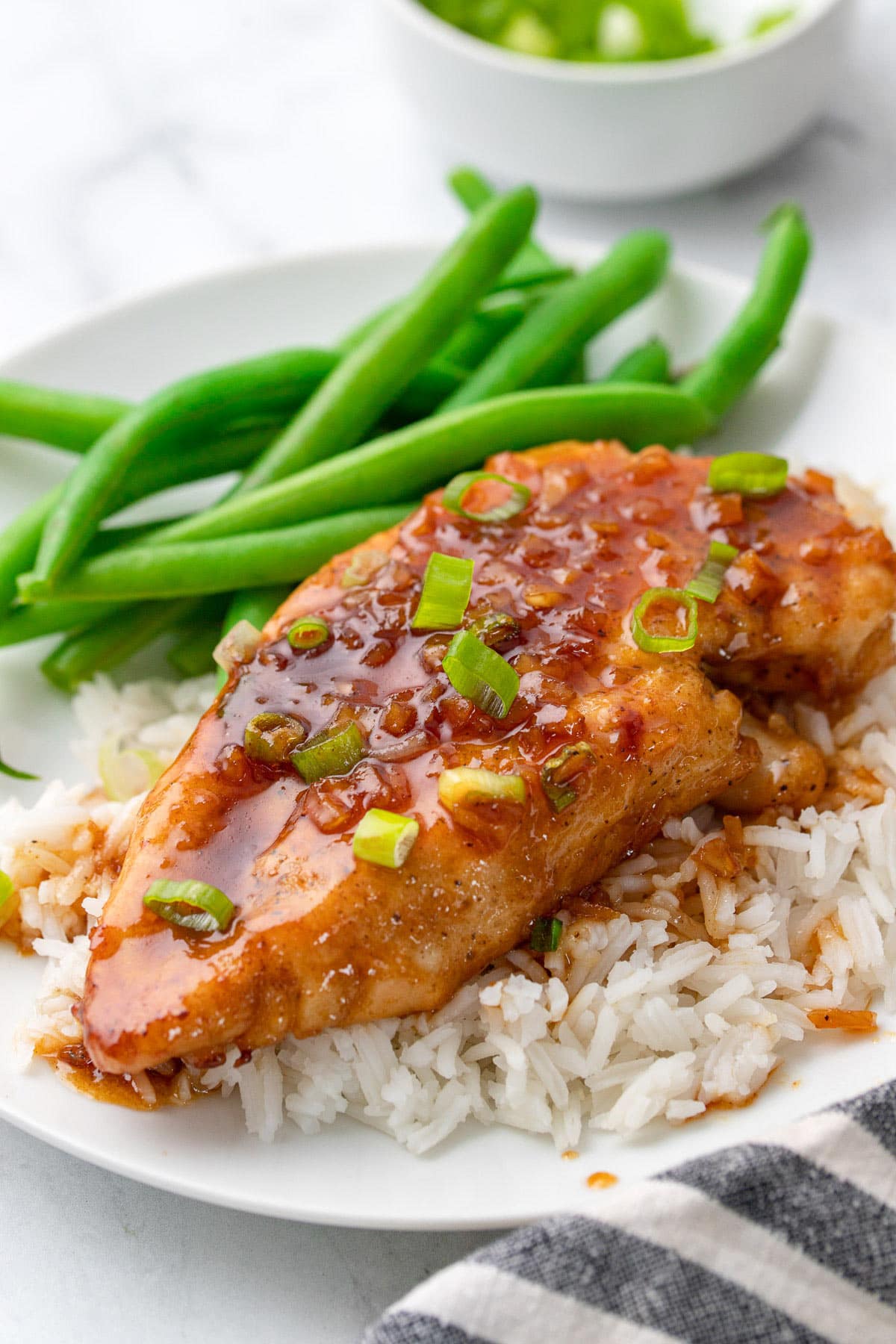 Honey garlic butter chicken on a bed of white rice with green beans.