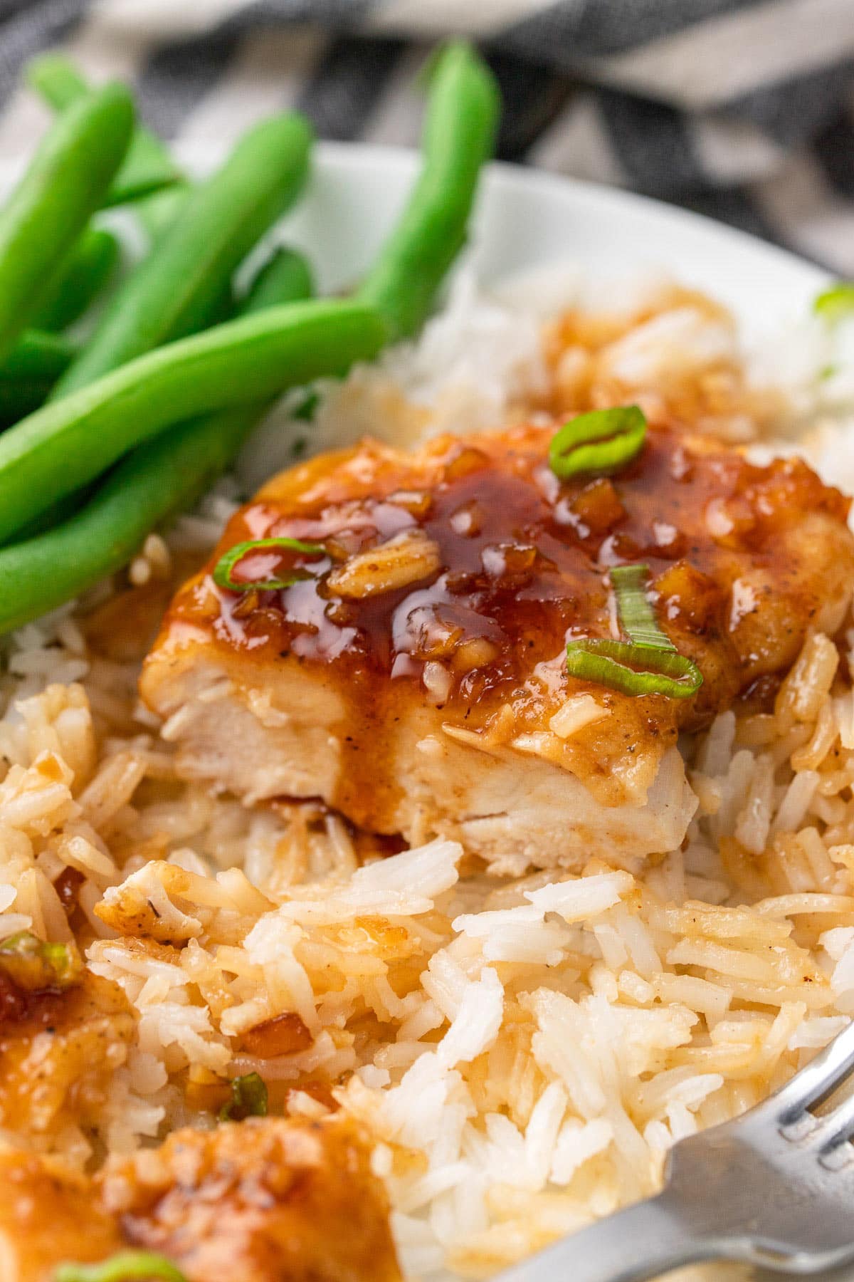 Honey garlic butter chicken on a bed of white rice with green beans.