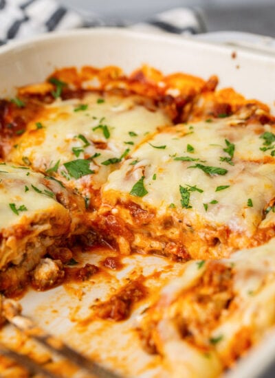 Ravioli lasagna bake in a white 9x13 casserole dish topped with freshly chopped parsley.
