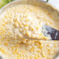 A heaping serving of creamed corn on a wooden spatula.