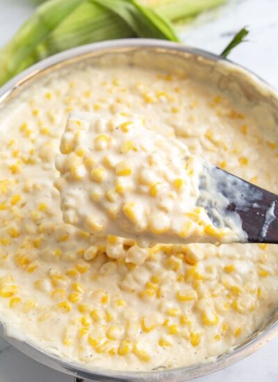 A heaping serving of creamed corn on a wooden spatula.