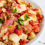 German potato salad in a white bowl topped with freshly chopped parsley.