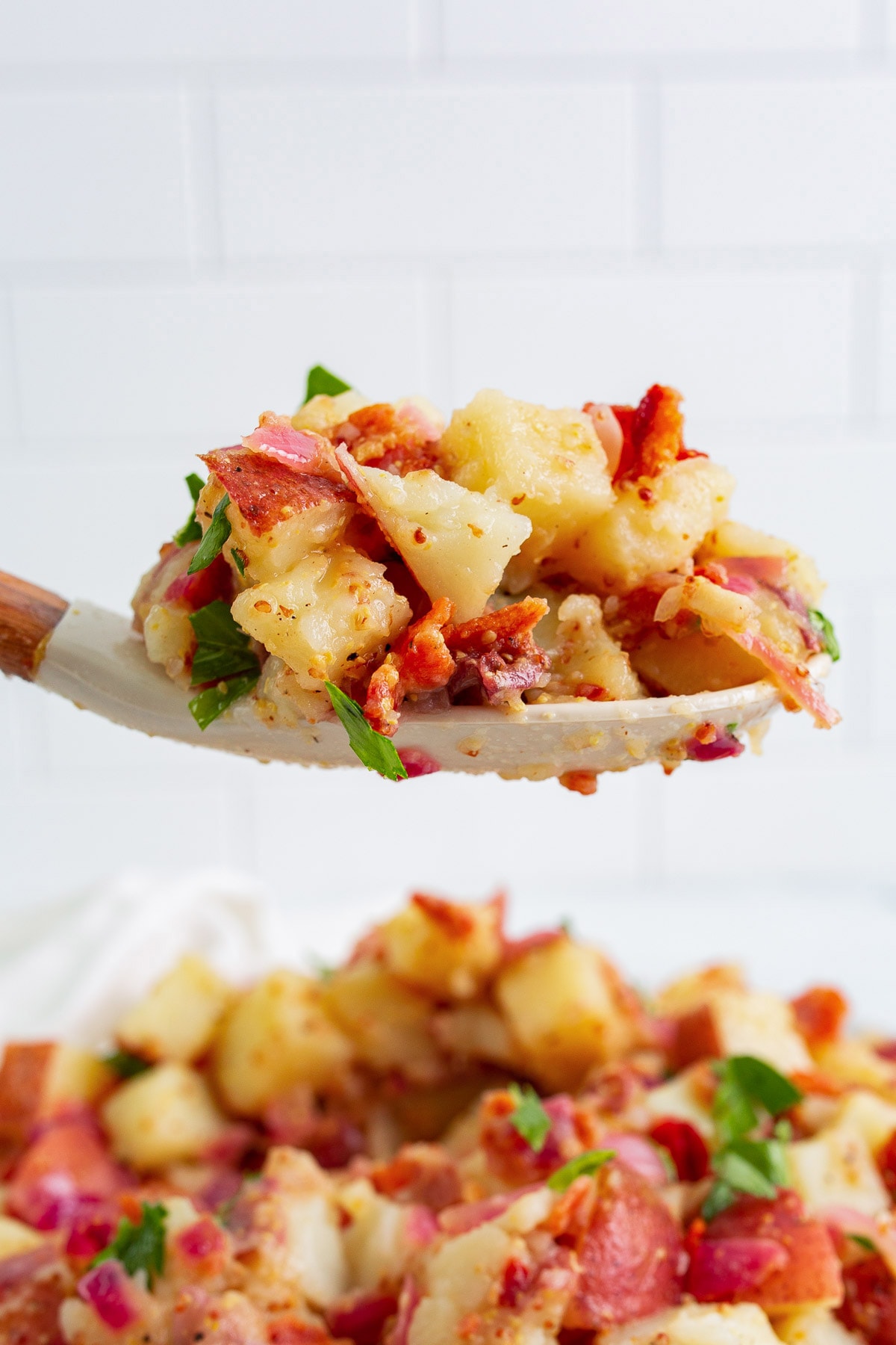A heaping spoonful of German potato salad topped with freshly chopped parsley.