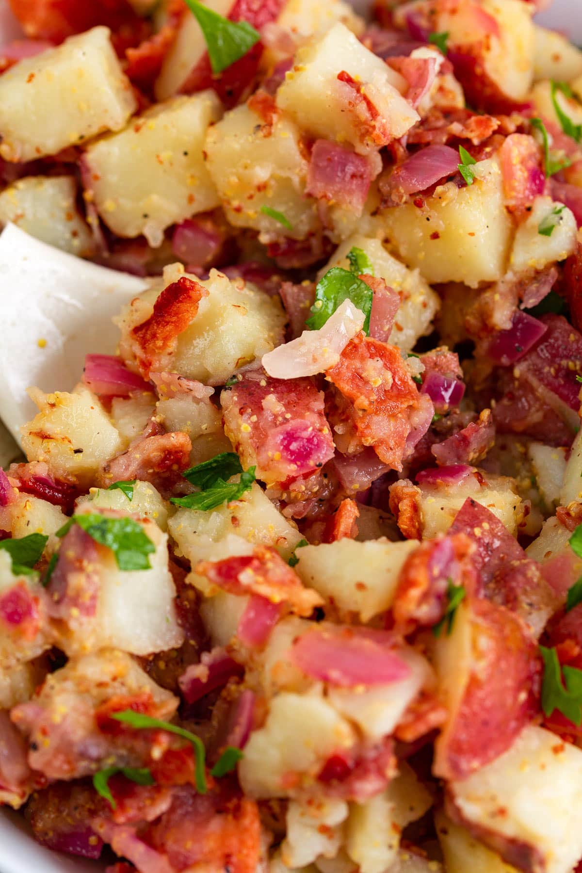 A close up image of German potato salad topped with freshly chopped parsley.