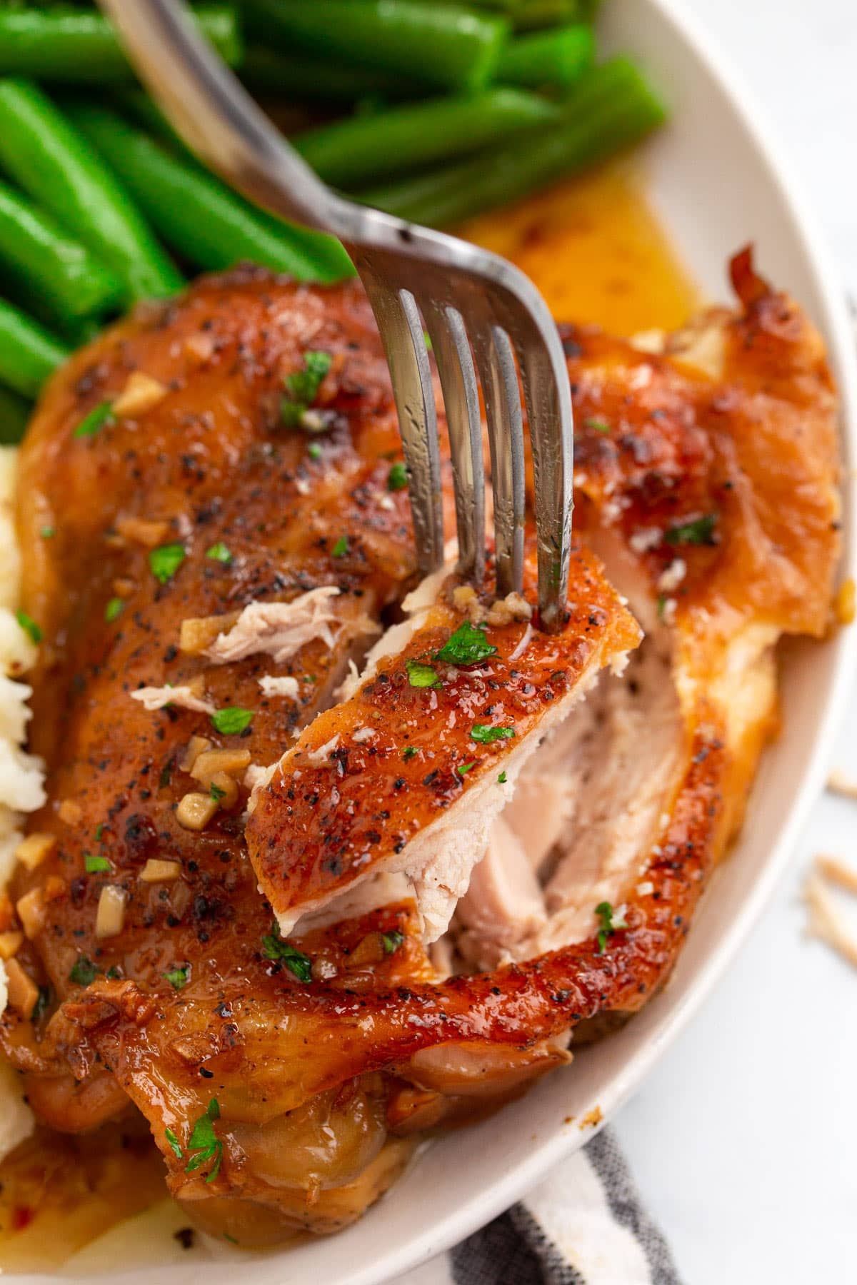 A bite-sized piece of slow cooker brown sugar galic chicken on a fork.