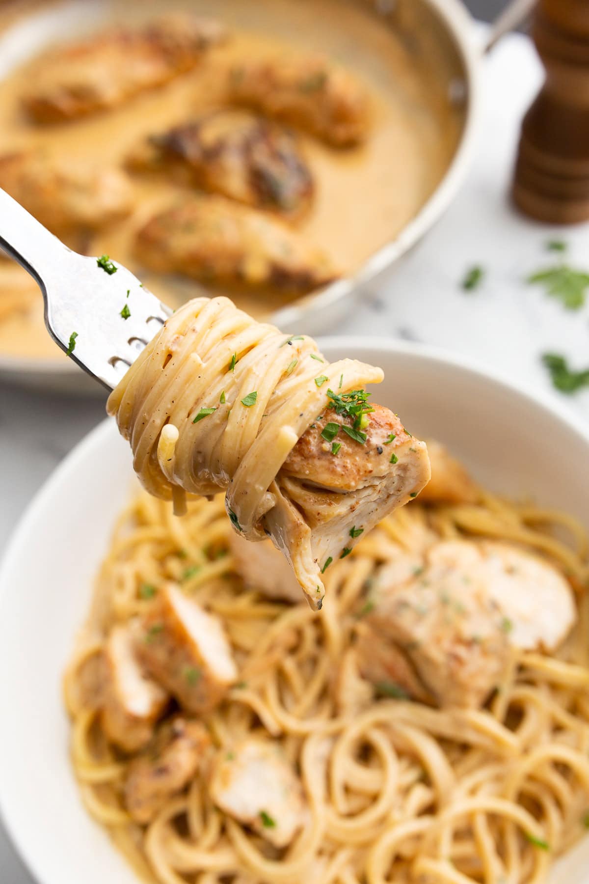 A forkful of creamy spaghetti with a bite-size piece of chicken Lazone.