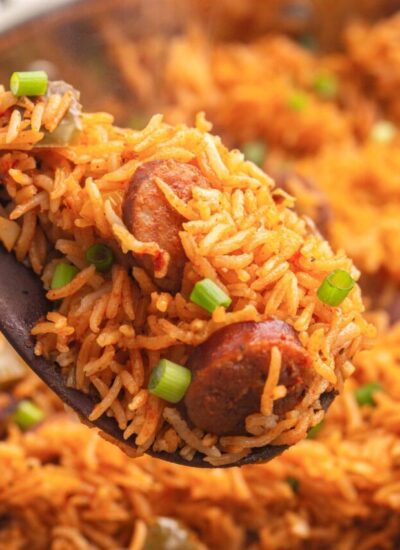 A heaping serving of smoked sausage and rice on a wooden spoon.