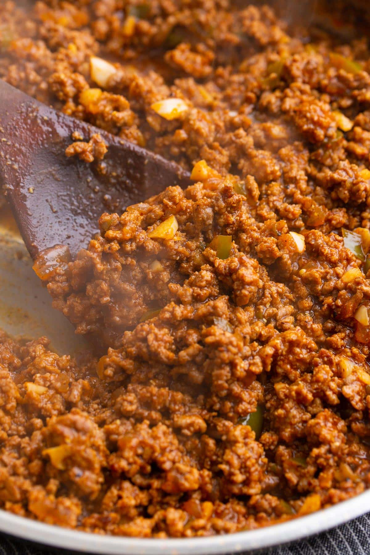 A close up photo of homemade Sloppy Joe sauce simmering in a stainless steel skillet.
