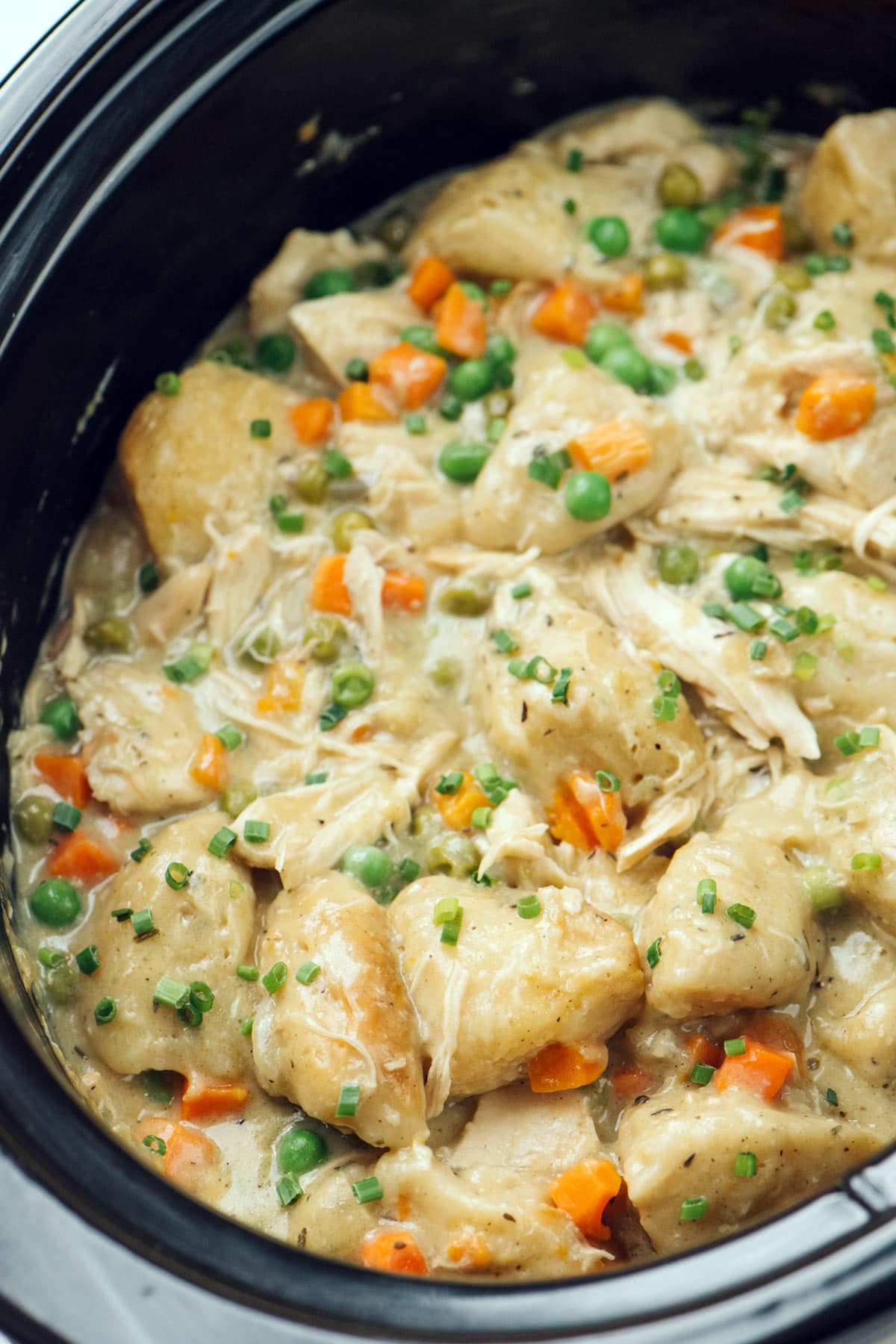 A close up photo of slow cooker chicken and dumplings in a crockpot.