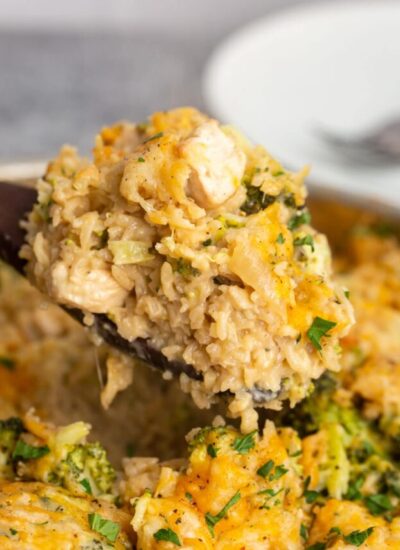 A heaping serving of one pot chicken broccoli rice casserole on a wooden serving spoon.