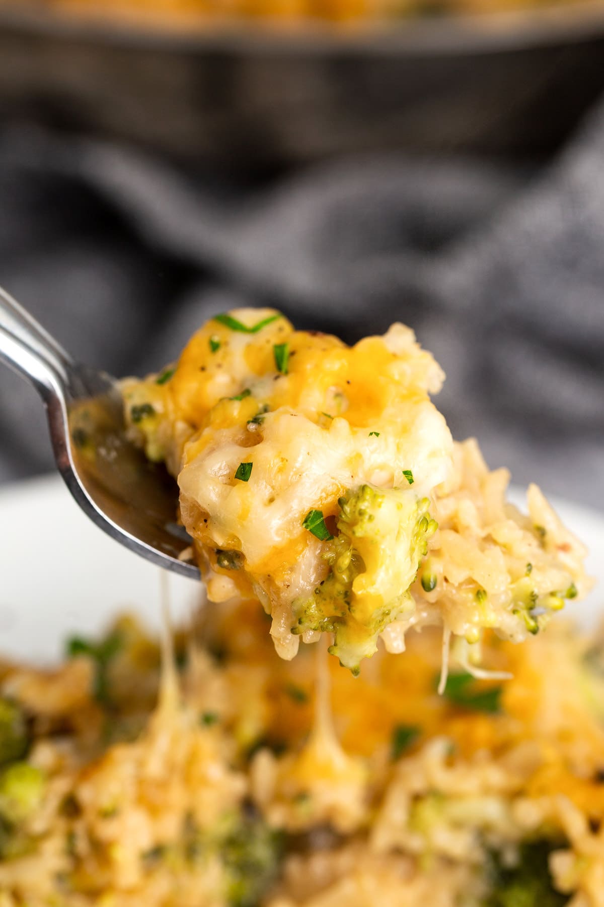 A forkful of chicken broccoli rice casserole with lots of cheese.