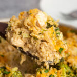 A heaping serving of one pot chicken broccoli rice casserole on a wooden serving spoon.