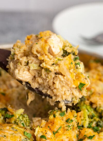 A heaping serving of one pot chicken broccoli rice casserole on a wooden serving spoon.