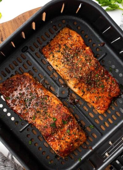 Easy air fryer salmon topped with fresh chopped parsley in an air fryer basket.