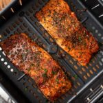 Easy air fryer salmon topped with fresh chopped parsley in an air fryer basket.