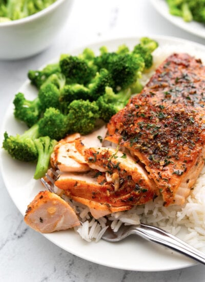 Easy air fryer salmon on a white dinner plate served with a side of white rice and broccoli.