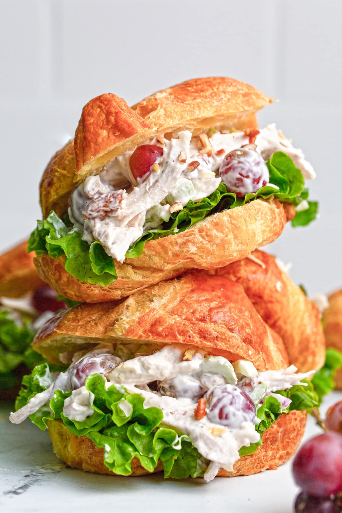 Two chicken salad croissant sandwiches stacked on top of each other.