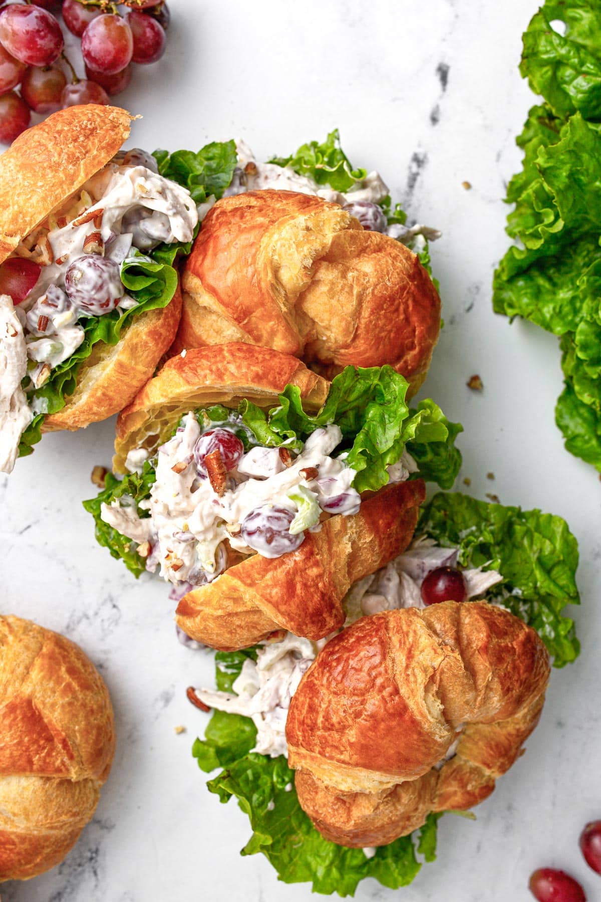 Four chicken salad croissant sandwiches stacked closely together.