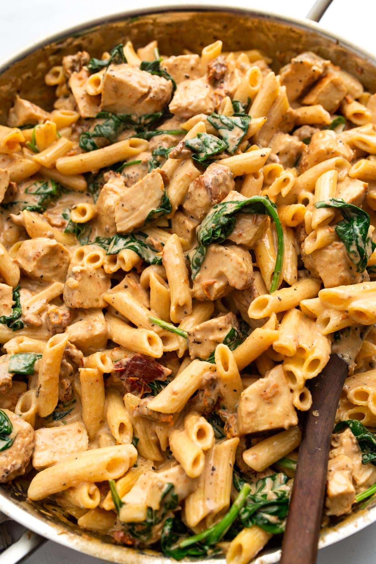 Creamy Tuscan chicken pasta in a stainless steel skillet.