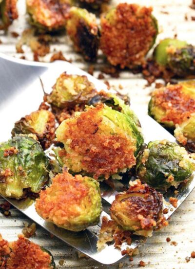 Several roasted crispy garlic Parmesan brussels sprouts scattered across a baking sheet.