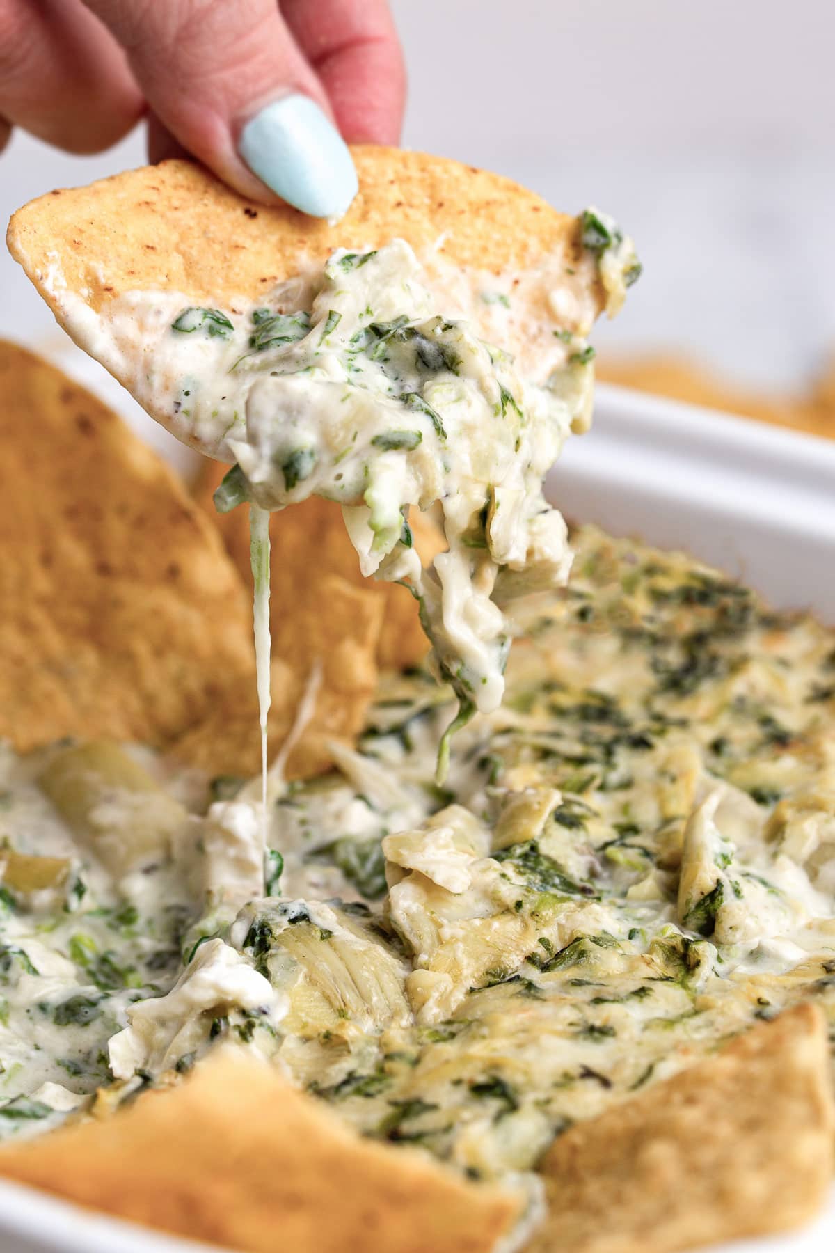 A tortilla dip dipped into spinach and artichoke dip.
