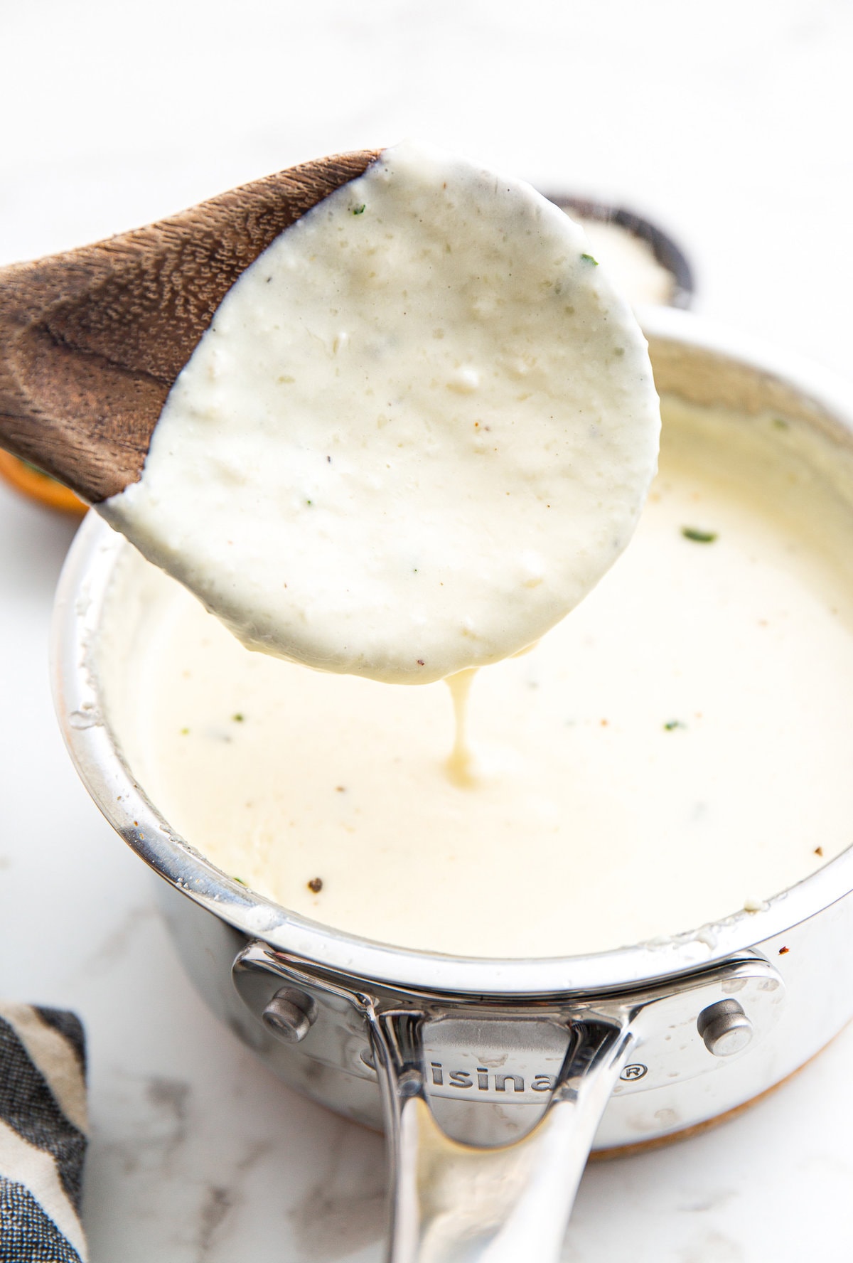 A portion of homemade Alfredo sauce on a wooden spoon.