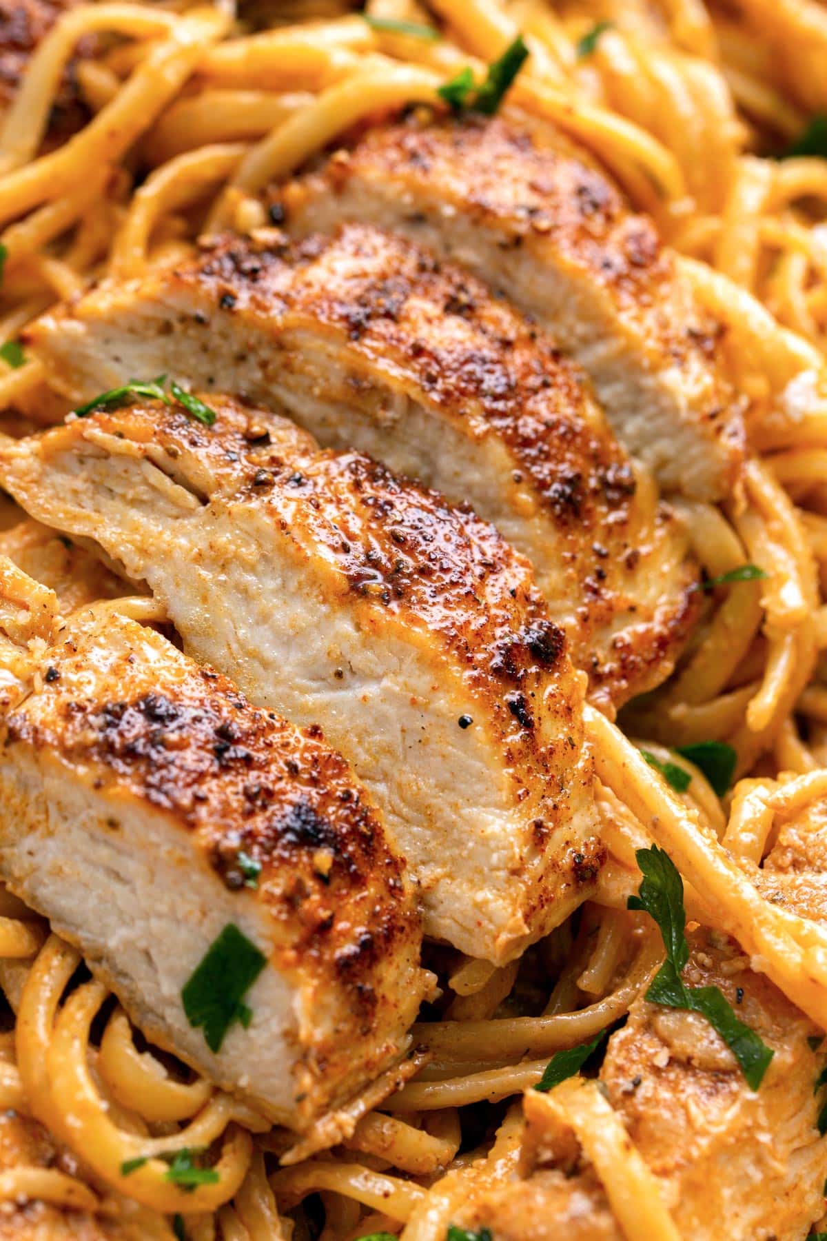 Thick slices of seared Cajun seasoned chicken on a bed of creamy pasta.